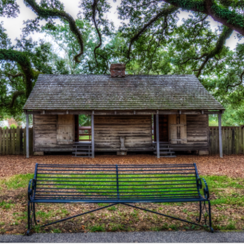 a wooden park bench sitting in front of a house